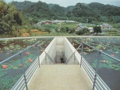 Water Temple by Tadao Ando, [lotus pond exterior / concrete wing walls / descent staircase / vermilion sanctuary interior / light court / Awaji Island hillside context], 1991 Japan