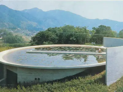 Water Temple by Tadao Ando, [lotus pond exterior / concrete wing walls / descent staircase / vermilion sanctuary interior / light court / Awaji Island hillside context], 1991 Japan