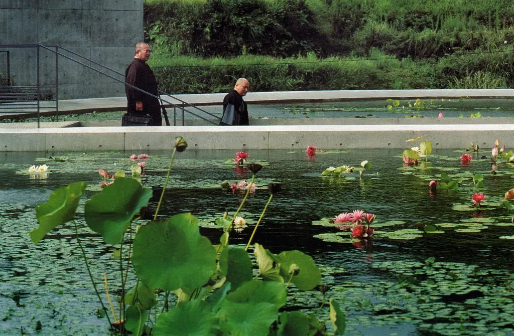 Water Temple by Tadao Ando, [lotus pond exterior / concrete wing walls / descent staircase / vermilion sanctuary interior / light court / Awaji Island hillside context], 1991 Japan
