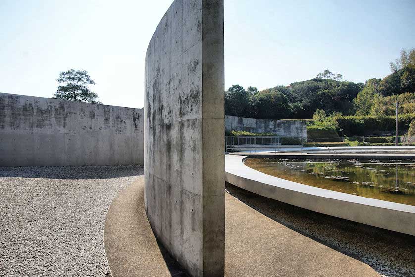Water Temple by Tadao Ando, [lotus pond exterior / concrete wing walls / descent staircase / vermilion sanctuary interior / light court / Awaji Island hillside context], 1991 Japan