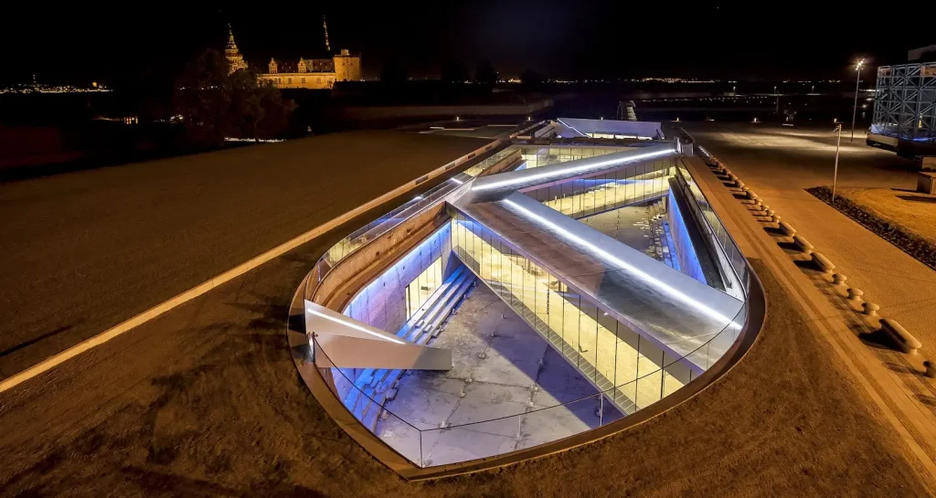 Danish National Maritime Museum by BIG Bjarke Ingels Group,
[aerial dry dock view / bridge spanning dock / underground gallery /
Kronborg Castle context / entrance zig-zag bridge / Morse code bollards /
auditorium bridge / dock interior], Helsingør Denmark 2013