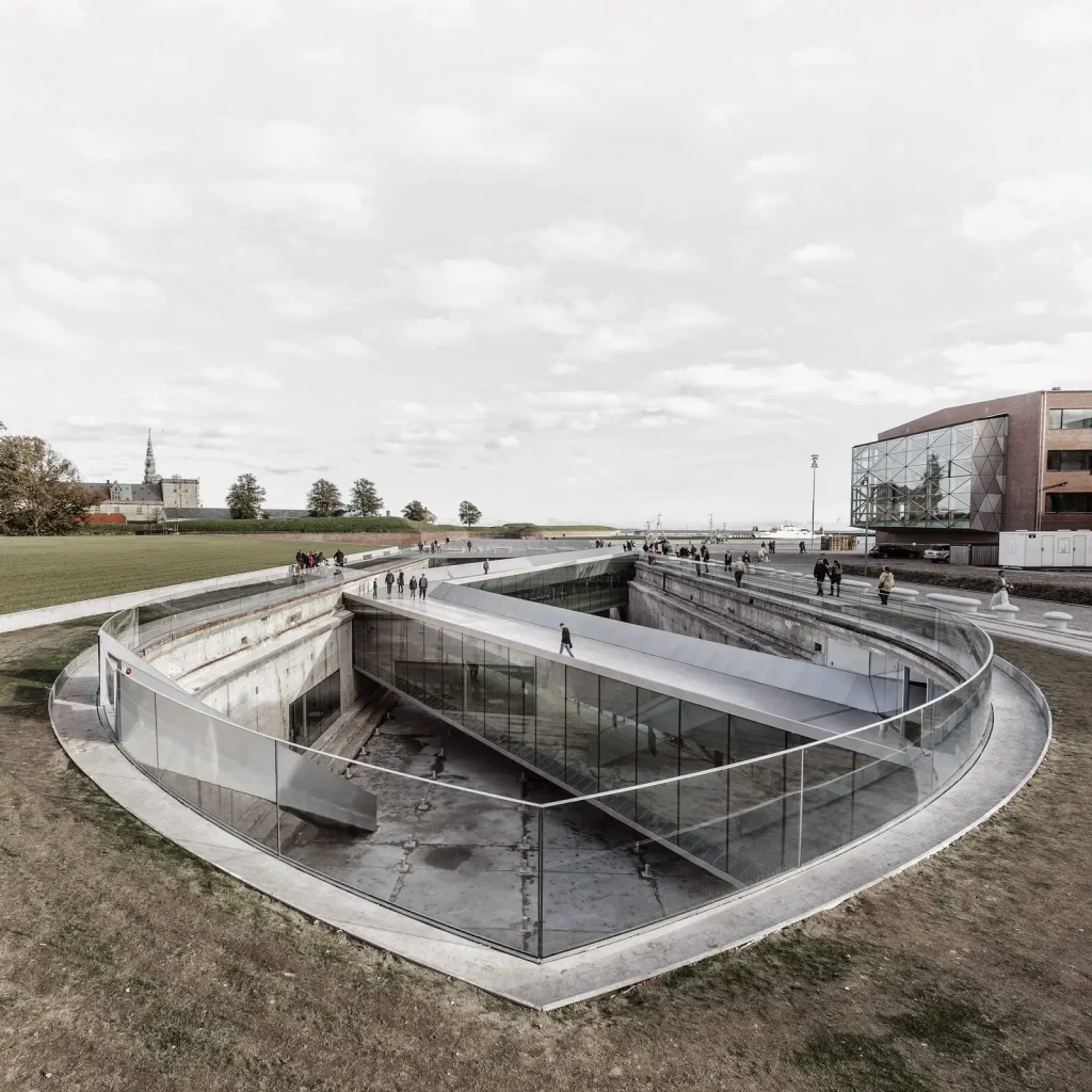 Danish National Maritime Museum by BIG Bjarke Ingels Group,
[aerial dry dock view / bridge spanning dock / underground gallery /
Kronborg Castle context / entrance zig-zag bridge / Morse code bollards /
auditorium bridge / dock interior], Helsingør Denmark 2013